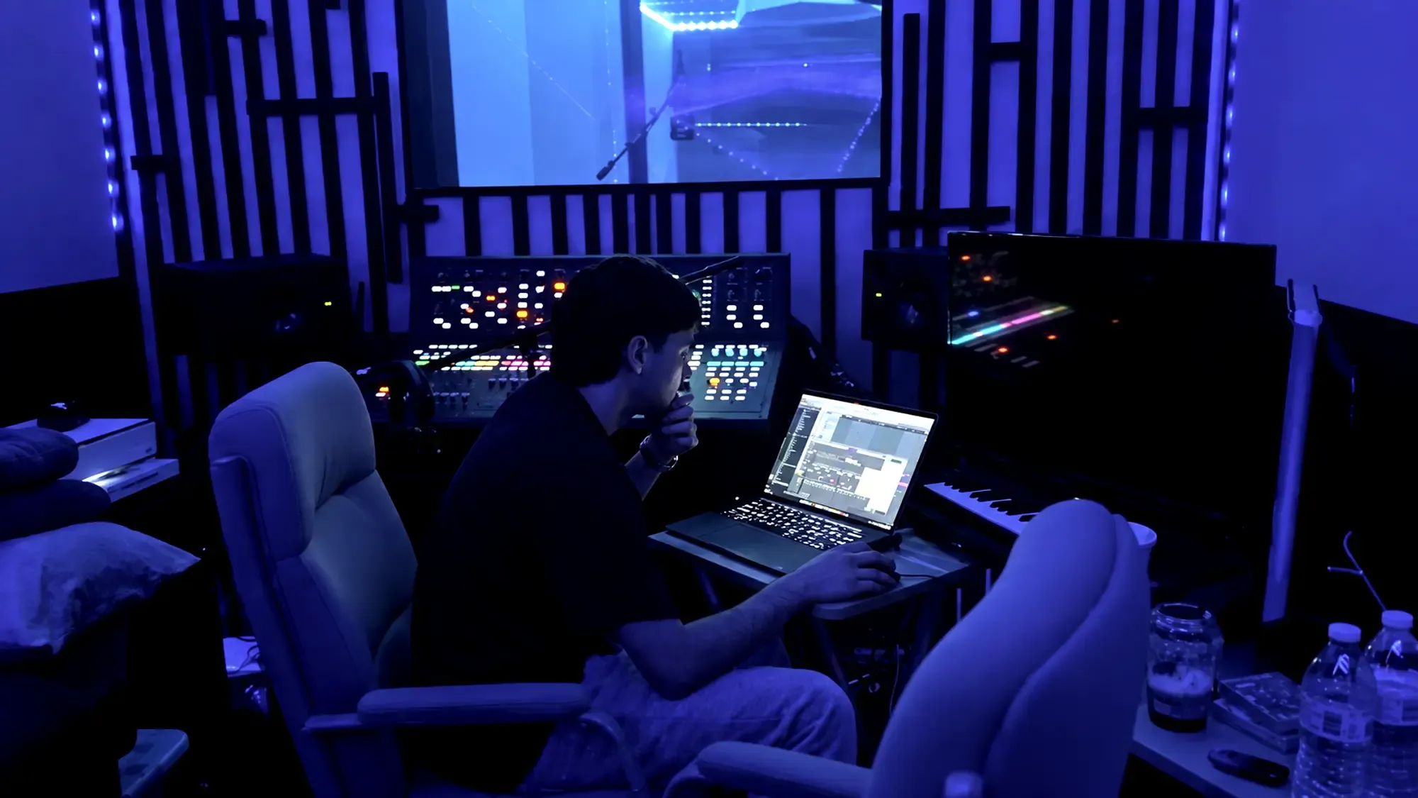 A producer at the desk late in a session, the mix open on the laptop