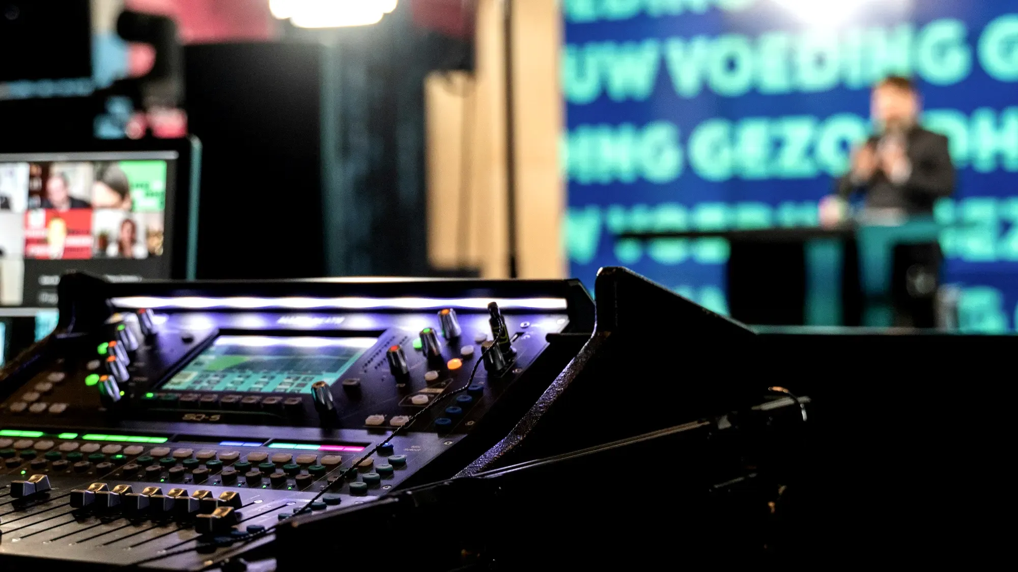 A digital mixing desk mid-show, the remote feed running on a laptop behind it